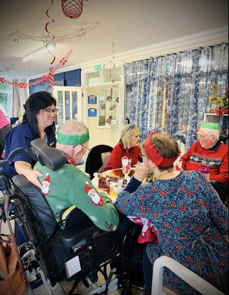 Festive fun in a care home, residents in hats and festive attire.